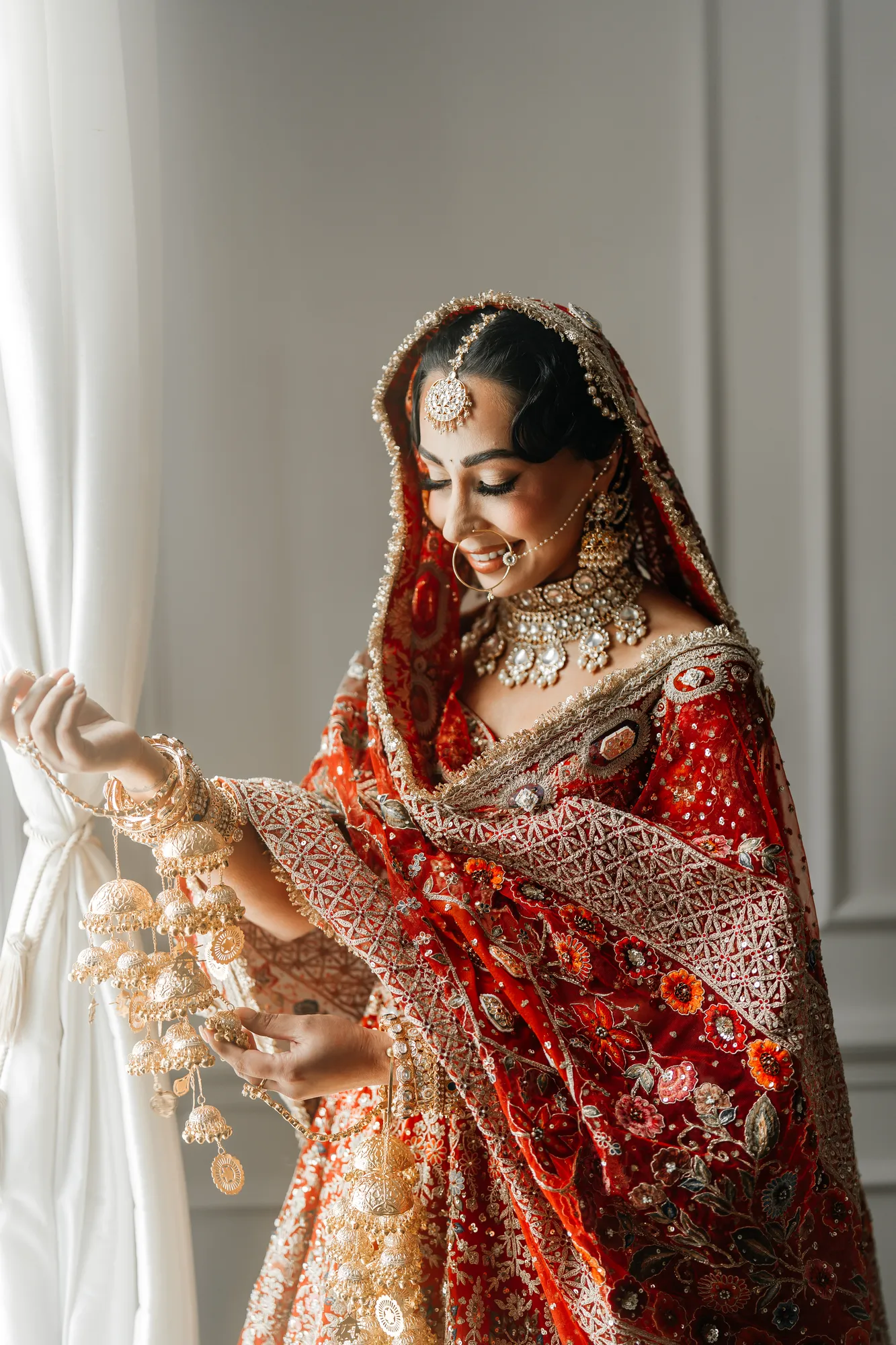 Bride holding wedding kalire beside a window